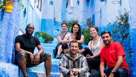 Travellers and leader pose for group shot in Chefchaouen's blue streets