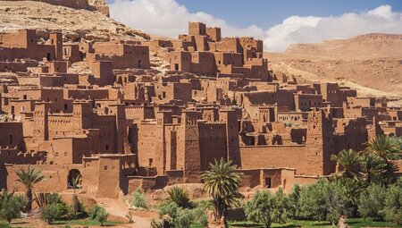 Ancient earthen city of Ait Benhaddou stacks up the hill of the desert in Morocco