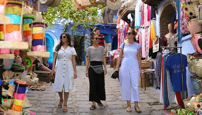 Travellers walking through colourful markets in Chefchaouen, Morocco