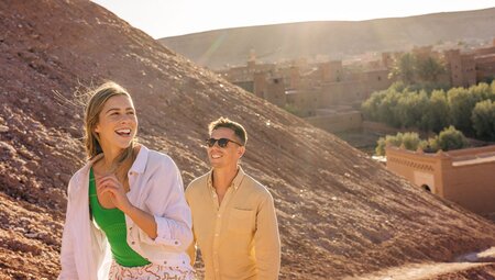 Travellers walking through Ait Benhaddou with mountains background, Morocco