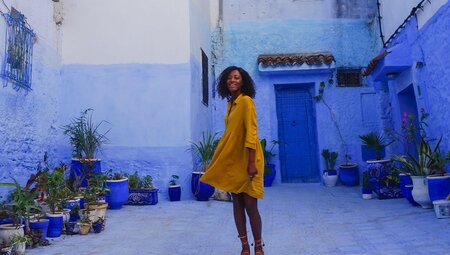 Female traveller posing among the bright blue walls in Chefchaouen, Morocco