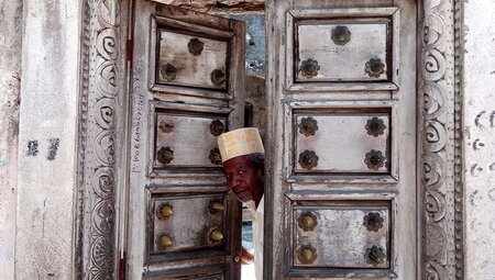 A local man peeking through the doors of a Medina in Moroni, Comoros Islands