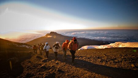 Travellers in a line approaching the peak of Kilimanjaro in Tanzania