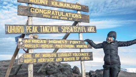 Intrepid traveller at Uhuru Peak summit sign, Mt Kilimanjaro, Tanzania