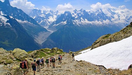 Group of hikers walking along bottom of Mont Blanc massif