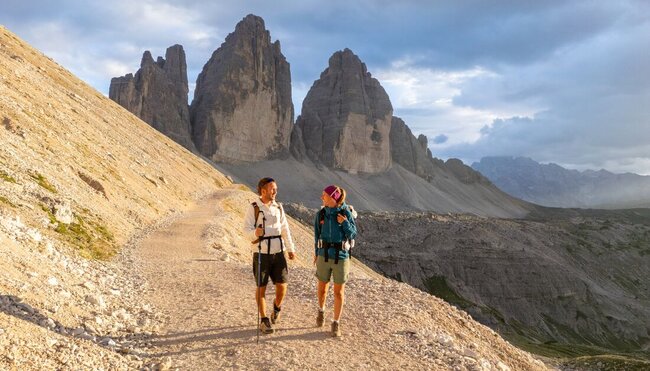Intrepid travellers talk and smile while hiking Tre Cime di Lavaredo in the Italian Dolomites