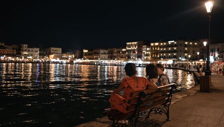 Group of Intrepid travellers and leader relax harbourside in Chania in the evening