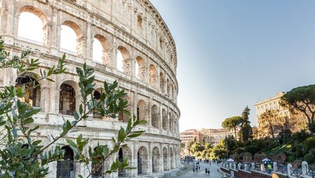 Iconic facade of Rome's Colosseum curves away from the camera with tiny crowds below for scale