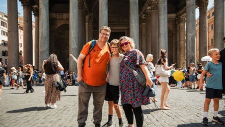 Intrepid traveller family posing for a photo in the streets of Rome outside the Pantheon in Italy
