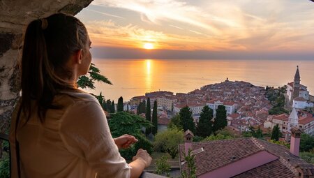 Teenage traveller looking out over Piran in Slovenia at sunset