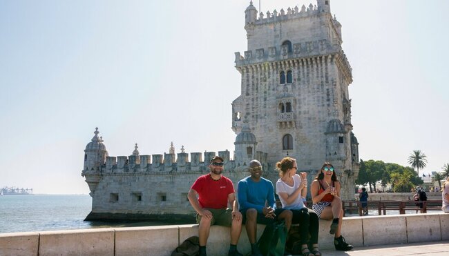 Travellers and leader sit outside the Belem tower on the waterfront of Portugal