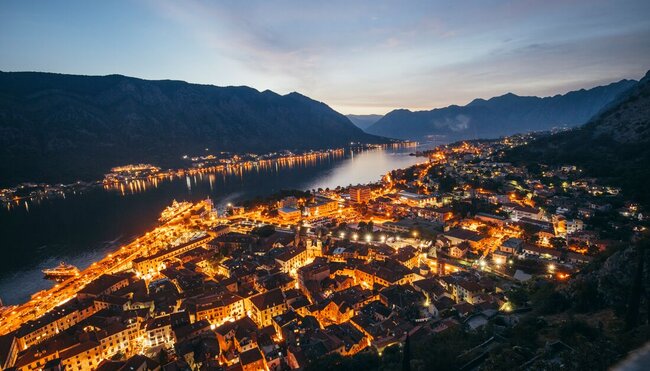 Aerial shot of Bay of Kotor in Montenegro at night time, with the town lights glowing