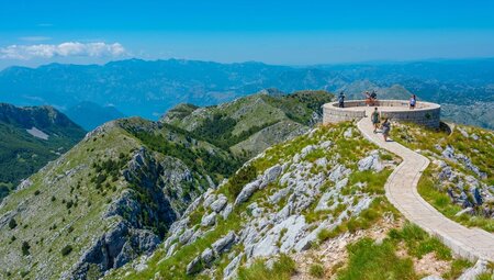 Wide shot of travellers walking on stone path along a rocky mountain in Lovcen National Park in Cetinje, Montenegro