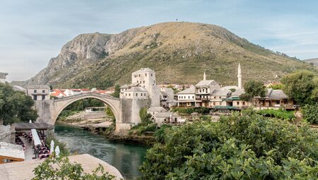 Wide shot of Mostar village with famous bridge in Bosnia and Herzegovina and mountains beyond