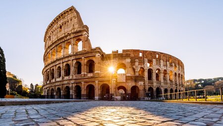 Sunrise beaming through an arch of the Colosseum
