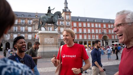 Group of travellers laugh as leader smiles in streeets of Madrid, Spain