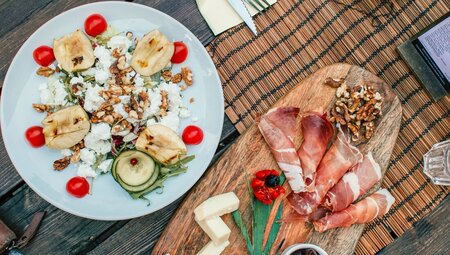 A top-down flatlay of mixed meats and picked vegetables for lunch in Ljubljana, Slovenia