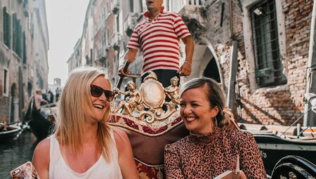 Two passengers take a gondola ride in Venice