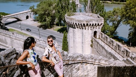 Travellers stop to rest on the stairs of a medieval castle in Avignon France