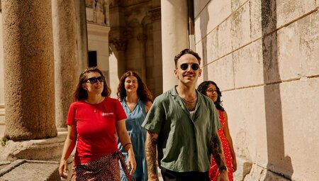 Traveller group and Leader smiling as they walk through Diocletian's Palace surrounded by cobblestone interior in Split, Croatia