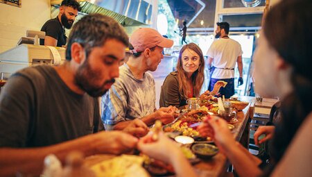 Group of travellers enjoying a meal together inside European restaurant