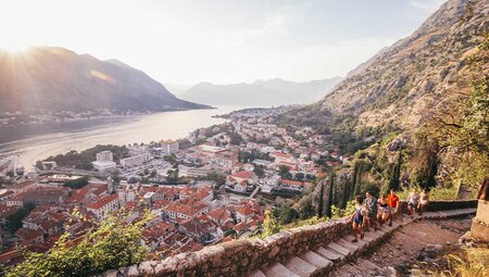 Travellers walk up steps to lookout over Koto harbour and city