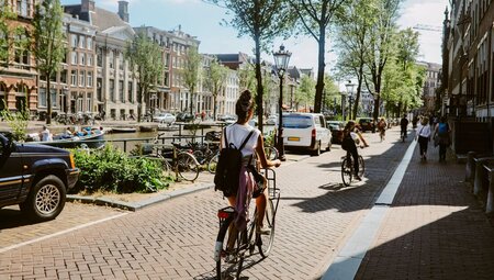 Travellers ride bikes alongside the canals of Amsterdam