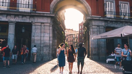 Intrepid travellers walk cobbled city street of Madrid with sunset, Spain