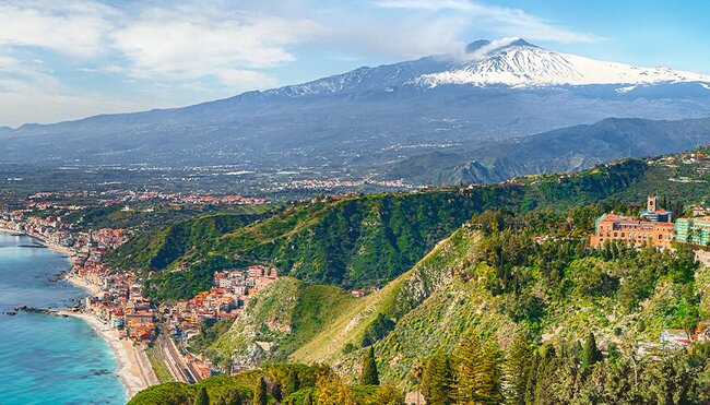 View of the town Taormini on the Sicilian coast with Mt. Etna in the background, Italy