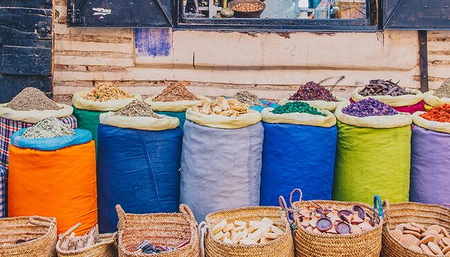 Local man sits at colouful spice market, Marrakech, Morocco