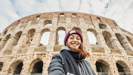 Traveller taking a selfing in front of the Colosseum in Rome, Italy.