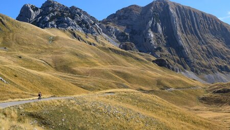Traveller at the head of group cycles through the mountains and meadows of Durmitor National Park, Montenegro