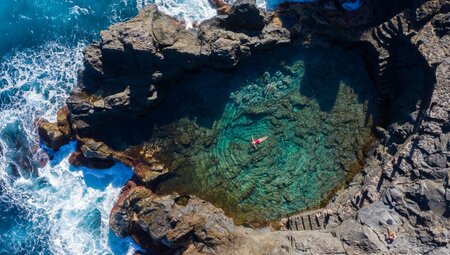 Traveller floats in natural coastal pools of El Calenton on Tenerife in the Canary Islands of Spain