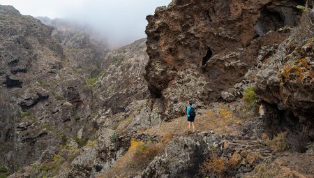 Travellers looks up at the surrounding mountains while hiking in Teno Rural Park in Tenerife