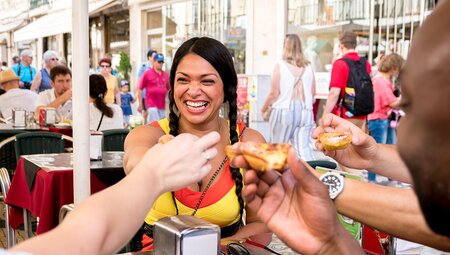 Travellers in Lisbon eating Portugese Custard Tarts on an Intrepid Travel tour.