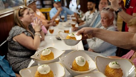 Group of Intrepid travellers being served artfully presented arancini balls in a Bareclona restaurant