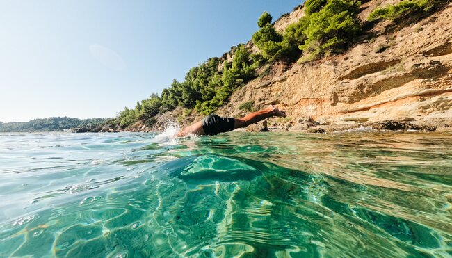 Intrepid traveller dives off submerged rock into the Aegean Sea off the coast of Alonnisos in the Sporades archipelago in Greece