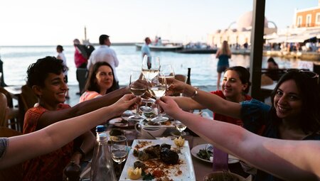 Intrepid travellers cheers in a seaside taverna in the Cyclades of Greece
