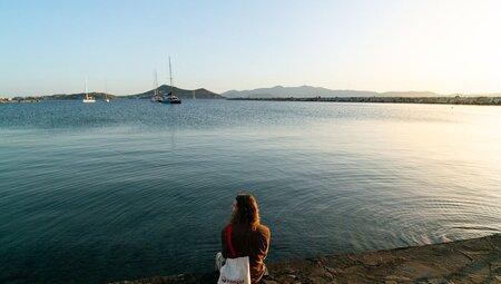 Intrepid traveller relaxing on rocky shore by the water on Naxos in Greece