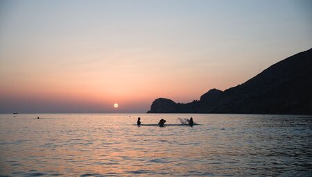 Intrepid travellers swimming and splashing in Syros at sunset