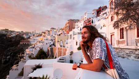 Traveller basks in the glow of the sunset in Santorini in the Cyclades of Greece