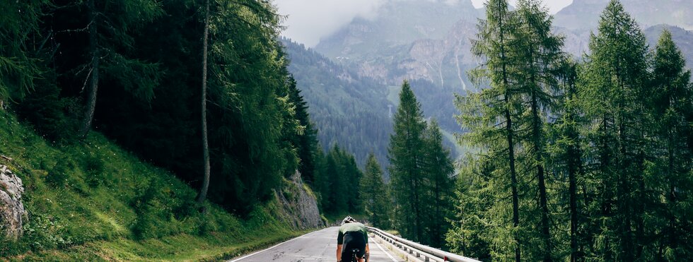 Professioneller Radfahrer mit schnellem und leichtem Kohlenstoff-Fahrrad steigt in den Alpen-Dolomiten auf die Bergstraße ab.