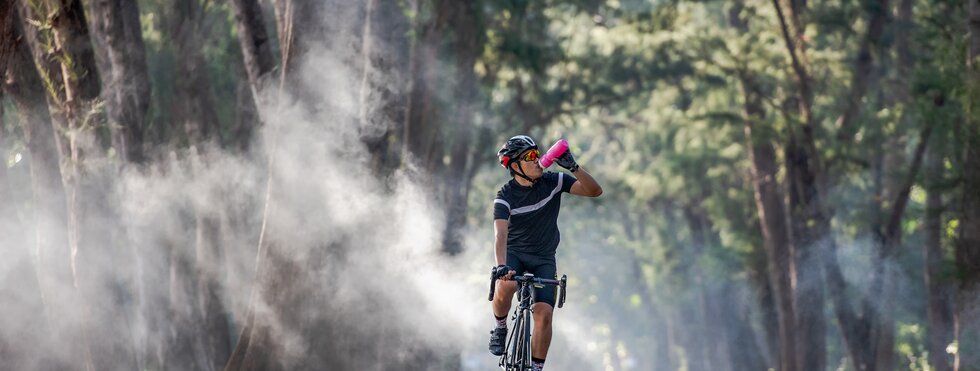Cyclist is drinking water from the sport bottle