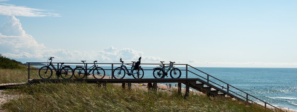 Die Silhouette der Fahrräder, die in einer Reihe an der Ostseeküste stehen.