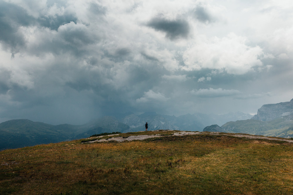 wolkenverhangener Himmel über offener Fläche, Berge im Hintergrund