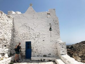 Weißes Mauerwerk einer Kirche, eine Person links von der kleinen blauen Tür