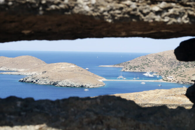 Perspektive durch Felsen hindurch, Blick auf felsige Bucht mit blauem Meer