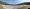 Panoramabild von Strand, kieseliger Boden, blaues Meehrwasser und Himmel