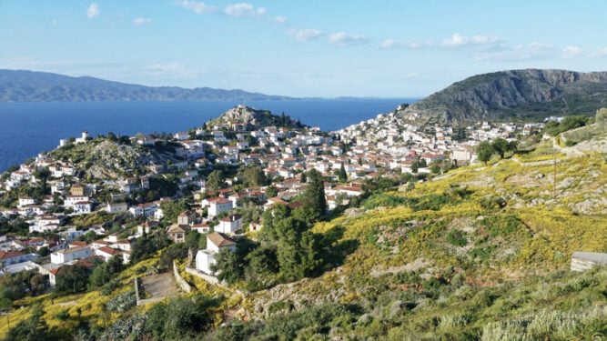 Aussicht über Wiesne mit gelben Blumen zu einer Stadt mit weißen Häusschen