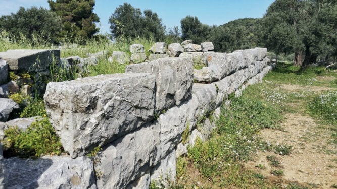 eine dicke Steinmauer in einer Wiese